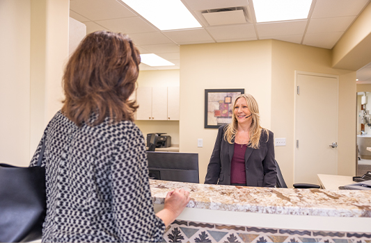 Dental team member at front desk smiling at a patient