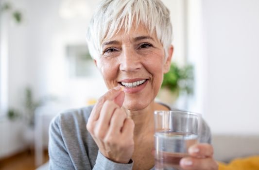 Woman holding pill and glass of water