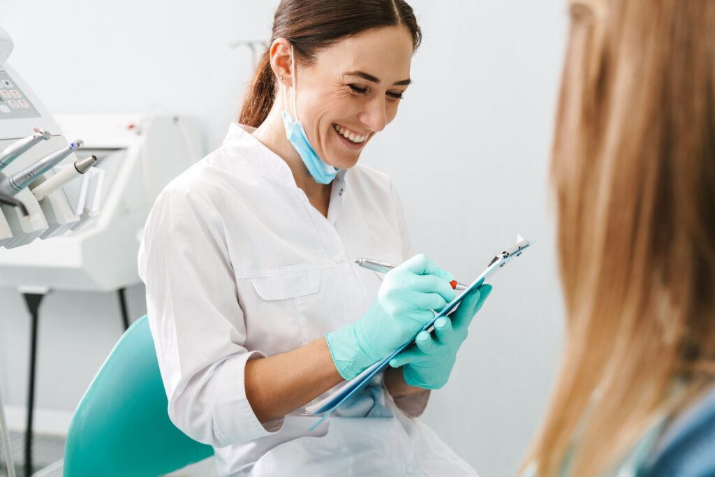Smiling dentist taking notes on clipboard