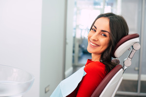 Female endodontic patient sitting back in treatment chair and smiling